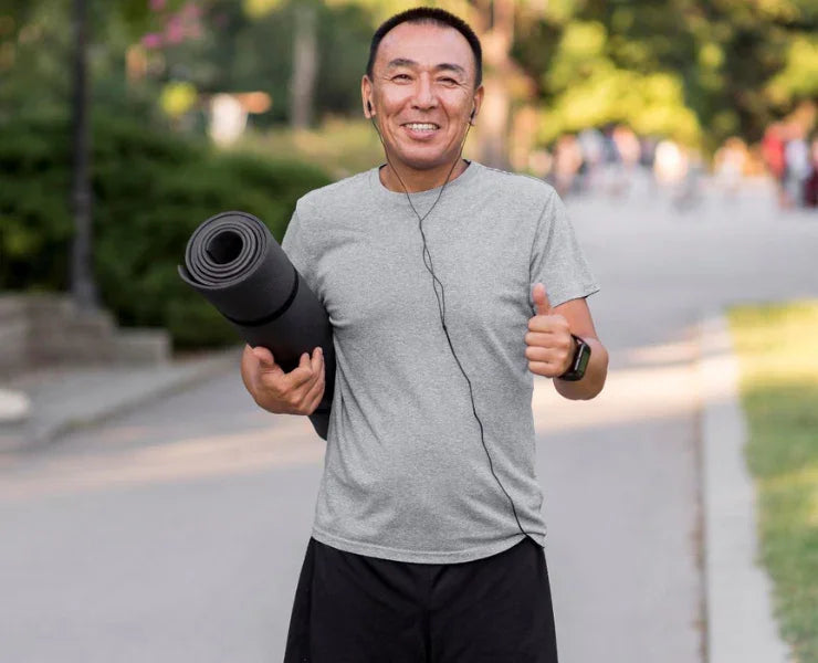 Homme de 50 ans avec un tapis de yoga et le pouce levé - Symbolise l'énergie et la vitalité naturelles apportées par l'eau hydrogénée